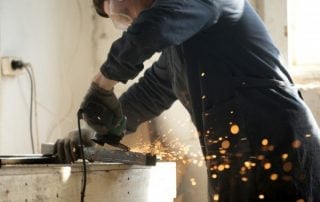 Skilled workman grinding metal pipe with a lot of sparks